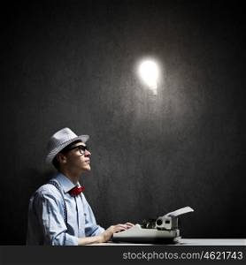Creative inspiration. Young funny man in glasses writing on typewriter