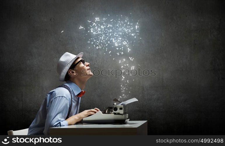 Creative inspiration. Young funny man in glasses writing on typewriter