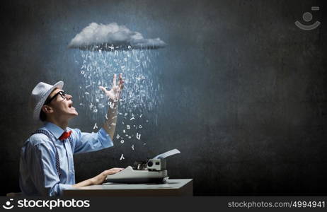 Creative inspiration. Young funny man in glasses writing on typewriter