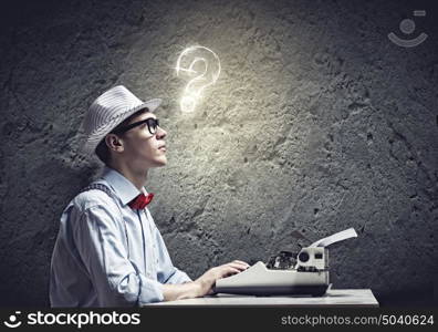 Creative inspiration. Young funny man in glasses writing on typewriter