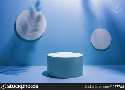 Creative layout made of blue studio background for product placement or display with a circular plinth in front of two blank round wall plaques with the shadows of palm tree fronds.
