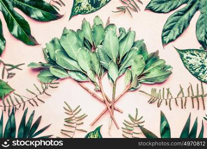 Creative layout made of tropical palm and fern leaves and branches on pastel pink background, top view, flat lay