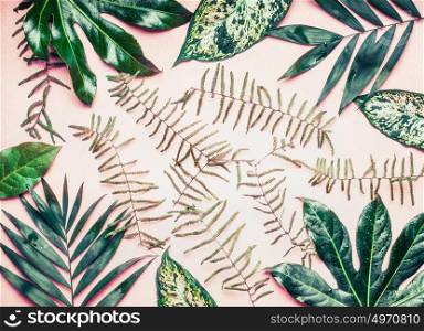 Creative layout made of various tropical palm and fern leaves on pastel pink background, top view, flat lay