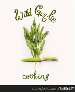 Creative layout with fresh green wild garlic leaves , knife and lettering text on white background. Healthy seasonal food, recipes and eating concept