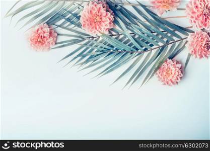 Creative layout with tropical palm leaves and pastel pink flowers on light turquoise blue desktop background, top view, place for text, horizontal
