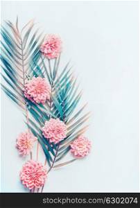 Creative layout with tropical palm leaves and pastel pink flowers on turquoise blue desktop background, top view, place for text, vertical