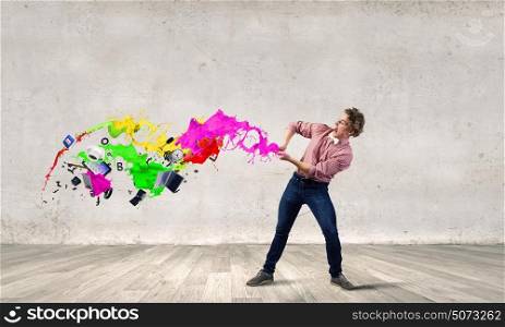 Creative manager. Young emotional man pulling colorful paint splashes