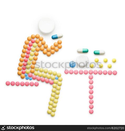 Creative medicine and healthcare concept made of drugs and pills; ill person sitting at the table and taking pills, isolated on white.