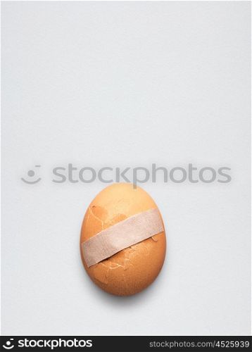 Creative medicine and healthcare concept, sticking plaster on cracked broken egg.