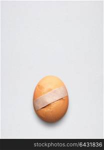 Creative medicine and healthcare concept, sticking plaster on cracked broken egg.
