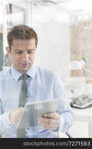Creative mid adult businessman holding digital tablet in office