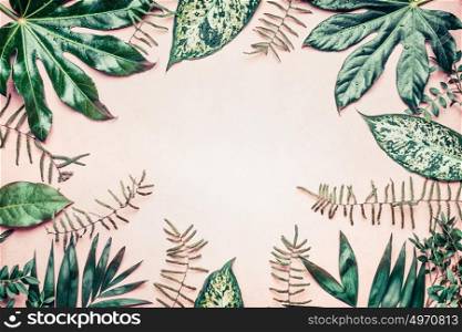 Creative nature frame made of tropical palm and fern leaves on pastel background, top view