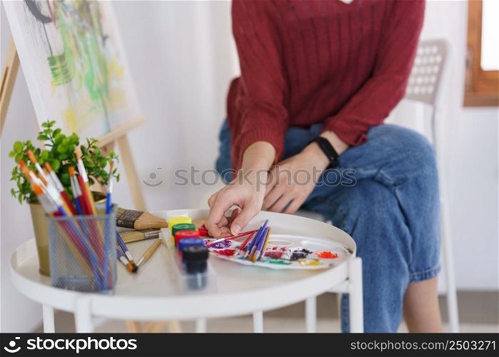 Creative of art concept, Young asian woman choose paintbrush for work to drawing artwork in studio.