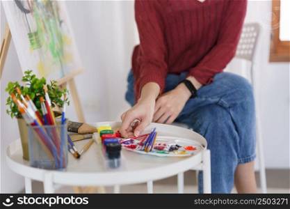 Creative of art concept, Young asian woman choose paintbrush for work to drawing artwork in studio.