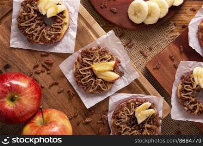 Creative party snack for holidays. Apple rounds with peanut butter, caramel and chocolate flavor puffed rice topping with banana slices. Funny appetizer for kids and adults.