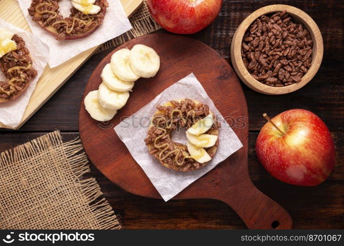 Creative party snack for holidays. Apple rounds with peanut butter, caramel and chocolate flavor puffed rice topping with banana slices. Funny appetizer for kids and adults.