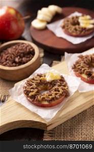 Creative party snack for holidays. Apple rounds with peanut butter, caramel and chocolate flavor puffed rice topping with banana slices. Funny appetizer for kids and adults.