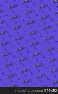Creative pattern from protective computer pixel glasses using for work with notebook screens, phones and TV on a dark lilac background.. Vertical pattern from protective art pixel glasses.