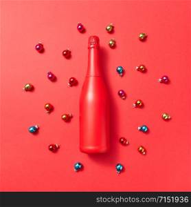 Creative pattern from red painted mock up bottle on a red background covered colored glass New Year balls with copy space. Greeting holiday card.. Holiday composition red painted mockup bottle on a Christmac background.