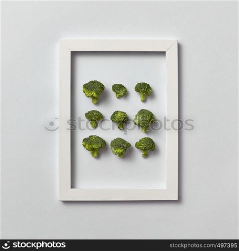 Creative pattern of natural freshly picked organic broccoli in a frame on a light gray background, place for text. Top view. Vegetarian food concept.. Fresh organic broccoli set in a frame on a light gray background.