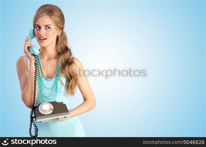 Creative photo of a pretty pin-up girl speaking via vintage phone on blue background.