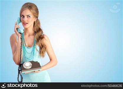 Creative photo of a pretty pin-up girl speaking via vintage phone on blue background.