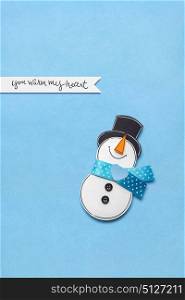 Creative photo of a snowman made of paper on blue background.