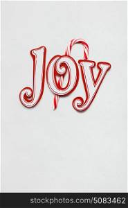 Creative photo of christmas candy and joy sign made of paper with on white background.