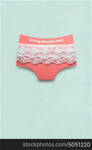 Creative photo of panties made of paper on mint background.