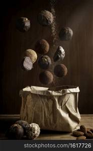 creative photography composition of delicious floating chocolate truffles and and craft paper bag on wooden background