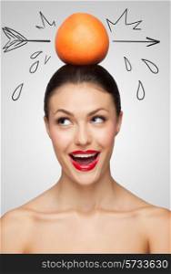 Creative portrait of a beautiful smiling woman holding a red grapefruit pierced with a sketchy arrow on her head.