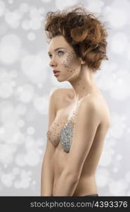 Creative portrait of sensual girl with brown elegant hair-style, naked shoulders and shiny decorations on make-up and breast