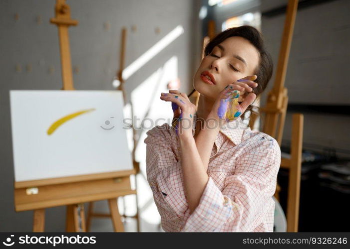 Creative portrait of young artist looking at camera through pa∫ed hands. Happy art school student headshot. Creative portrait of young artist looking at camera through pa∫ed hands