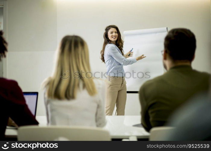 Creative positive female leader talking about business plan with students during workshop in the small office