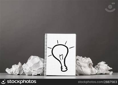 creative process. crumpled wads and notebook with bulb picture