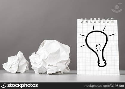 creative process. crumpled wads and notebook with bulb picture