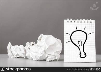 creative process. crumpled wads and notebook with bulb picture