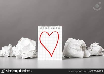 creative process. crumpled wads and notebook with heart picture