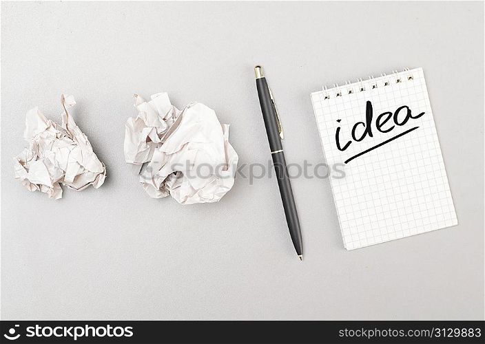 creative process. crumpled wads and notebook with idea word