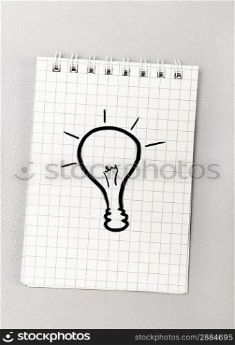 creative process. notebook with bulb picture on gray