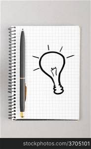 creative process. notebook with bulb picture on gray
