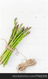 Creative scandinavian style flat lay top view mockup of fresh green asparagus on white wooden table background copy space. Minimal house cooking concept mock up for blog or recipe book