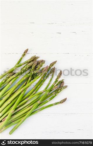 Creative scandinavian style flat lay top view mockup of fresh green asparagus on white wooden table background copy space. Minimal house cooking concept mock up for blog or recipe book