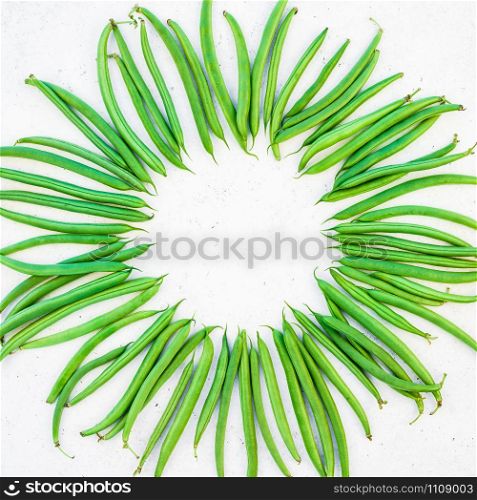 Creative scandinavian style flat lay top view of fresh green beans on white concrete table background copy space. Minimal house cooking concept template for blog or recipe book