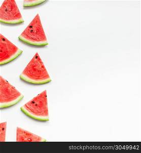 Creative scandinavian style flat lay top view of fresh watermelon slices on white table background copy space. Minimal summer fruits pattern for blog or recipe book
