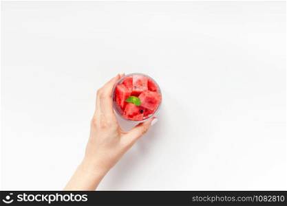 Creative scandinavian style flat lay top view of fresh watermelon slices smoothie drink in glass woman hands on white table background copy space. Minimal summer fruits concept for blog or recipe book