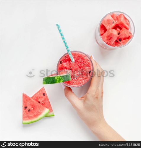 Creative scandinavian style flat lay top view of fresh watermelon slices smoothie drink in glass woman hands on white table background copy space. Minimal summer fruits concept for blog or recipe book