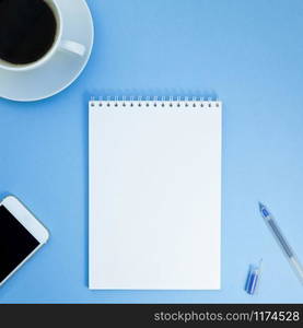 Creative square flat lay photo of workspace desk with paper notebook, smartphone, pen and coffee with copy space background minimal style