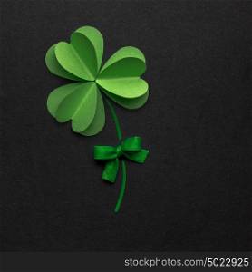 Creative St. Patricks Day concept photo of a shamrock made of paper on black background.