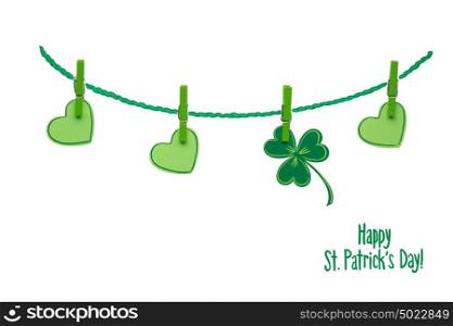 Creative St. Patricks Day concept photo of pinned shamrocks and hearts made of paper on white background.